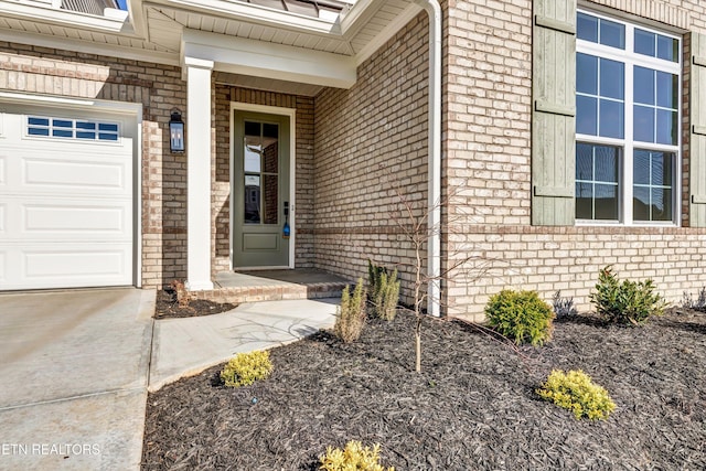 view of exterior entry with a garage and brick siding