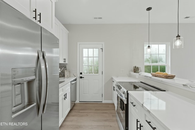 kitchen with stainless steel appliances, pendant lighting, white cabinets, and light wood-style floors