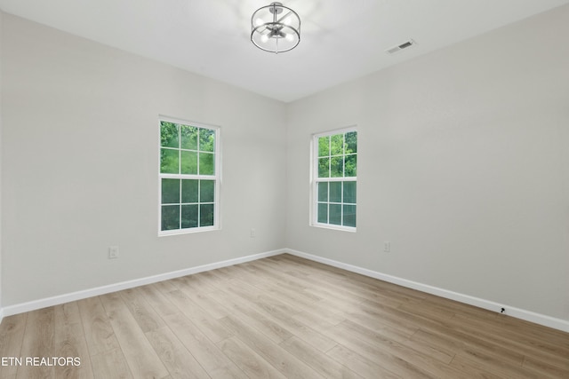 empty room with light wood-type flooring, baseboards, and visible vents