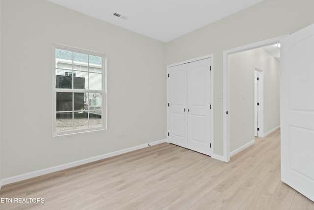 unfurnished bedroom featuring a closet, visible vents, light wood-style flooring, and baseboards