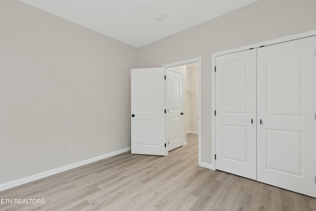 unfurnished bedroom featuring baseboards, a closet, and light wood-style floors