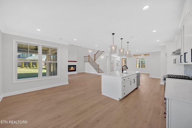 kitchen with open floor plan, light wood-type flooring, recessed lighting, a warm lit fireplace, and white cabinetry