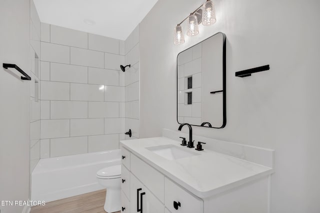 bathroom featuring bathing tub / shower combination, toilet, wood finished floors, and vanity