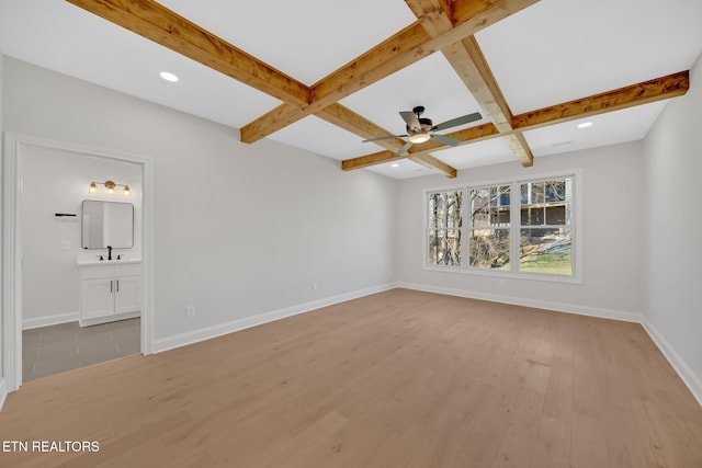 unfurnished bedroom featuring beamed ceiling, light wood-style flooring, and baseboards