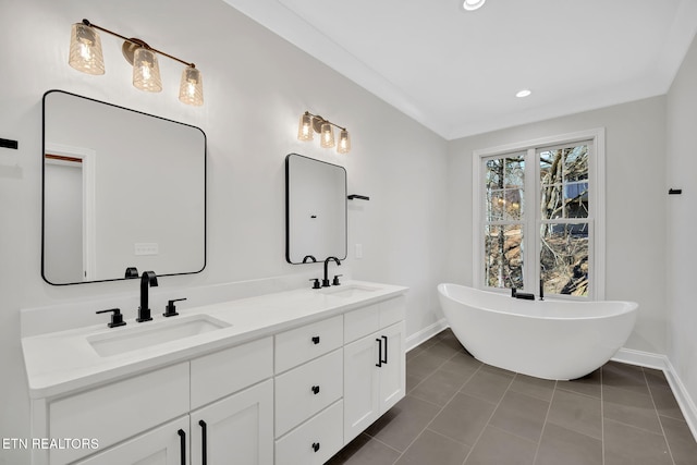 bathroom with double vanity, a freestanding tub, tile patterned floors, and a sink