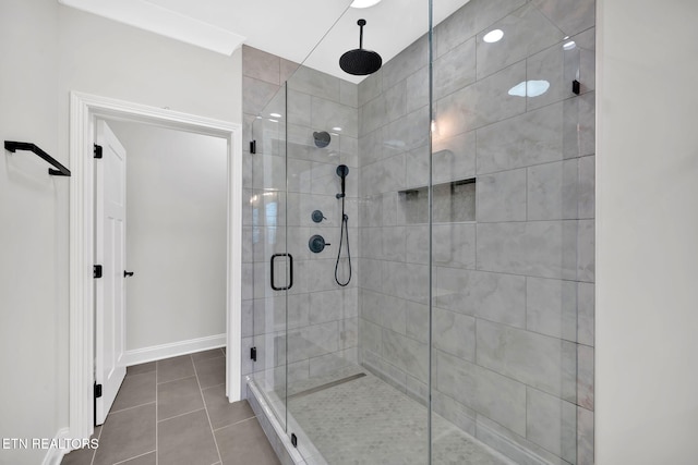 full bath featuring tile patterned flooring, a shower stall, and baseboards