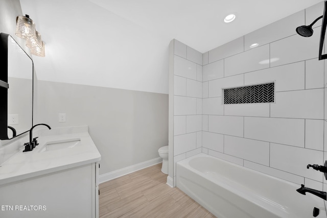 bathroom with toilet, a sink, wood finished floors, double vanity, and baseboards