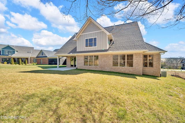 rear view of house featuring brick siding, board and batten siding, central AC, a lawn, and a patio area