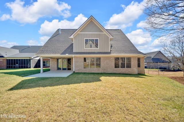 rear view of property featuring a yard, brick siding, board and batten siding, and a patio area