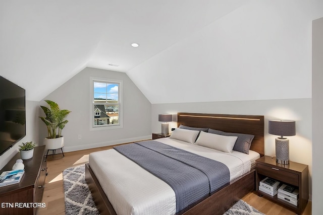 bedroom featuring baseboards, lofted ceiling, visible vents, and light wood finished floors