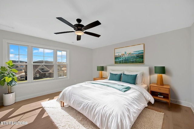 bedroom with visible vents, baseboards, wood finished floors, and a ceiling fan