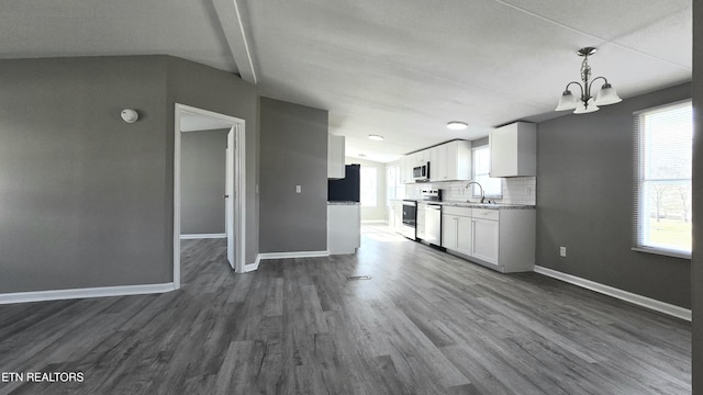 kitchen with appliances with stainless steel finishes, tasteful backsplash, white cabinetry, sink, and hanging light fixtures