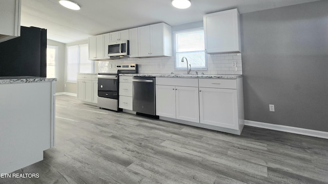 kitchen with appliances with stainless steel finishes, sink, white cabinets, and decorative backsplash