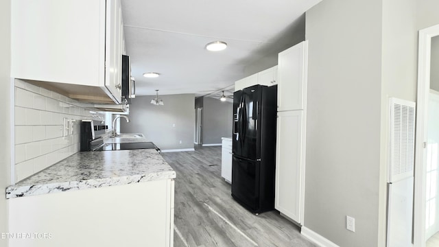 kitchen with tasteful backsplash, white cabinetry, sink, light wood-type flooring, and black refrigerator with ice dispenser