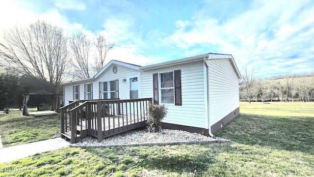 manufactured / mobile home featuring a front lawn, a carport, and a deck