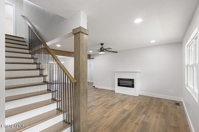 stairs featuring decorative columns, wood-type flooring, and ceiling fan