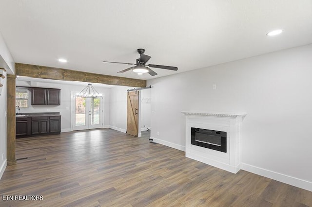 unfurnished living room with a barn door, sink, dark hardwood / wood-style flooring, and french doors