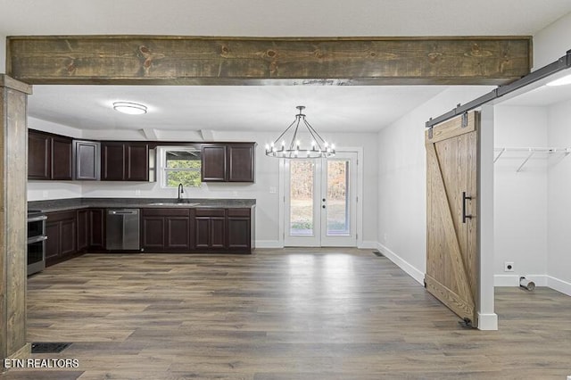 kitchen with pendant lighting, sink, stainless steel dishwasher, dark brown cabinetry, and a barn door