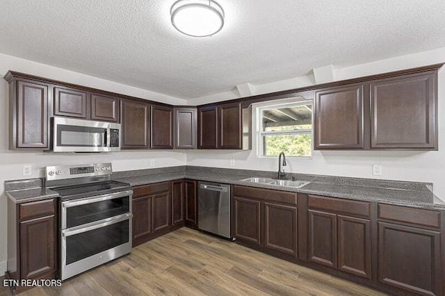 kitchen featuring sink, stainless steel appliances, dark hardwood / wood-style floors, dark brown cabinetry, and a textured ceiling