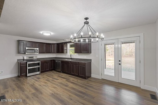 kitchen with appliances with stainless steel finishes, decorative light fixtures, sink, dark hardwood / wood-style flooring, and dark brown cabinets