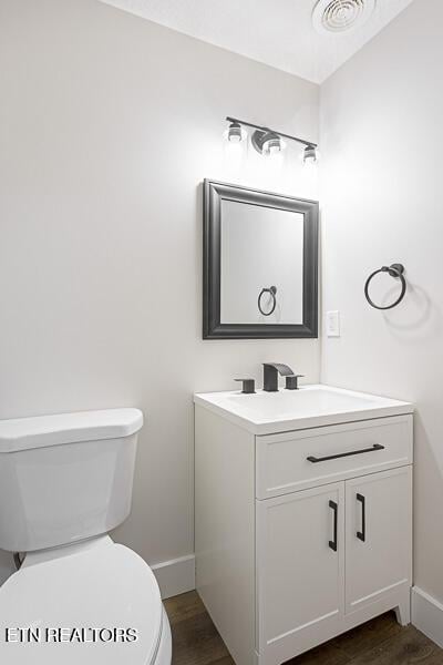 bathroom with vanity, hardwood / wood-style floors, and toilet