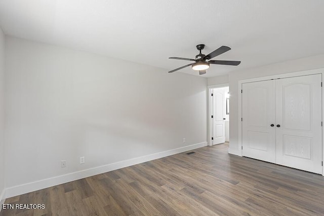 unfurnished bedroom featuring dark hardwood / wood-style flooring, a closet, and ceiling fan