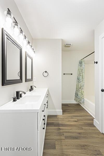 bathroom with shower / tub combo with curtain, hardwood / wood-style floors, and vanity