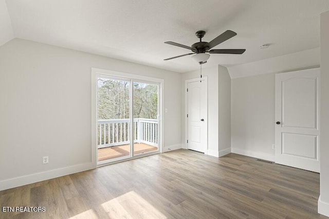 unfurnished bedroom with vaulted ceiling, hardwood / wood-style floors, access to exterior, and ceiling fan