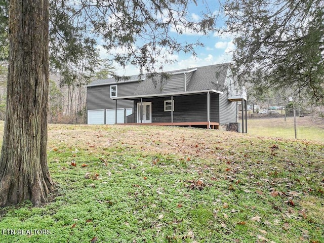 rear view of property featuring a garage and a lawn