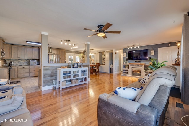 living area with track lighting, light wood-type flooring, visible vents, and a ceiling fan