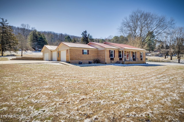 view of front of home featuring brick siding, covered porch, an attached garage, crawl space, and metal roof