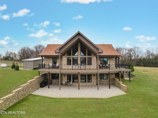 rear view of property with a patio, a yard, a wooden deck, and brick siding