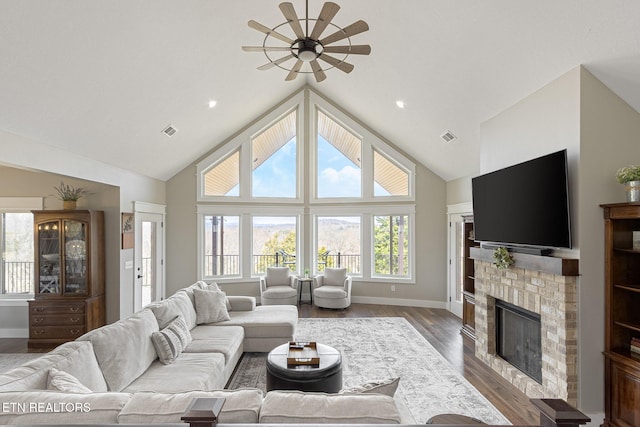 living area featuring high vaulted ceiling, visible vents, a fireplace, and wood finished floors