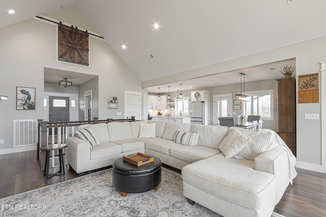 living area with dark wood finished floors, recessed lighting, visible vents, a barn door, and baseboards