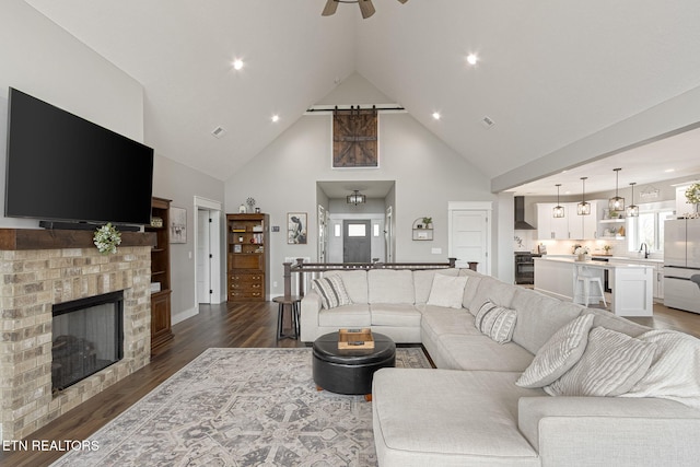 living area with a healthy amount of sunlight, a fireplace, high vaulted ceiling, and dark wood-type flooring