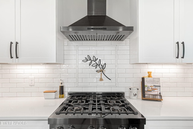 kitchen featuring island range hood, range with gas stovetop, white cabinets, light countertops, and tasteful backsplash