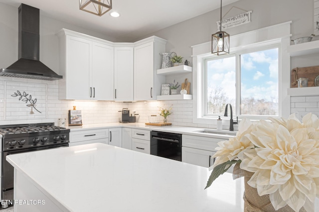 kitchen featuring black dishwasher, stainless steel range, light countertops, white cabinetry, and wall chimney range hood