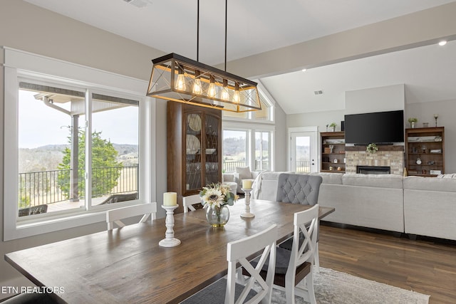 dining room with lofted ceiling, dark wood-style flooring, visible vents, and a fireplace