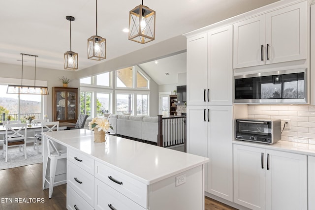 kitchen with pendant lighting, light countertops, stainless steel microwave, and white cabinets