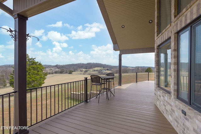 wooden terrace with a rural view and a lawn