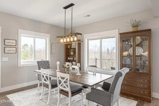 dining area with wood finished floors, visible vents, and baseboards