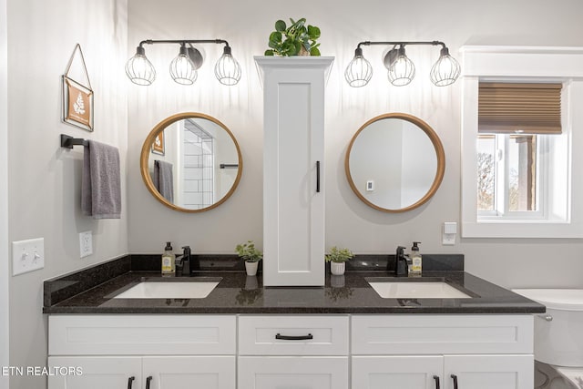 full bath with a sink, toilet, and double vanity