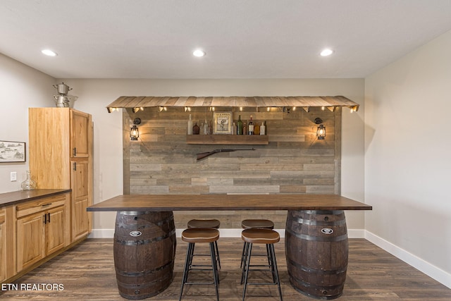 bar with a bar, baseboards, dark wood finished floors, and recessed lighting