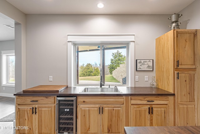 kitchen with wine cooler, dark countertops, visible vents, a sink, and wood finished floors