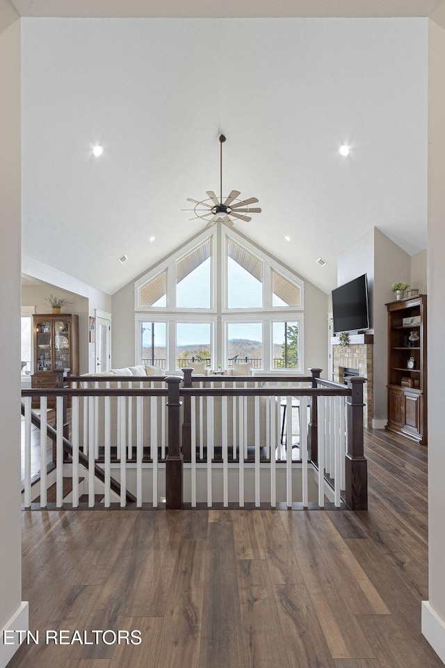 corridor featuring lofted ceiling, dark wood-style floors, and an upstairs landing