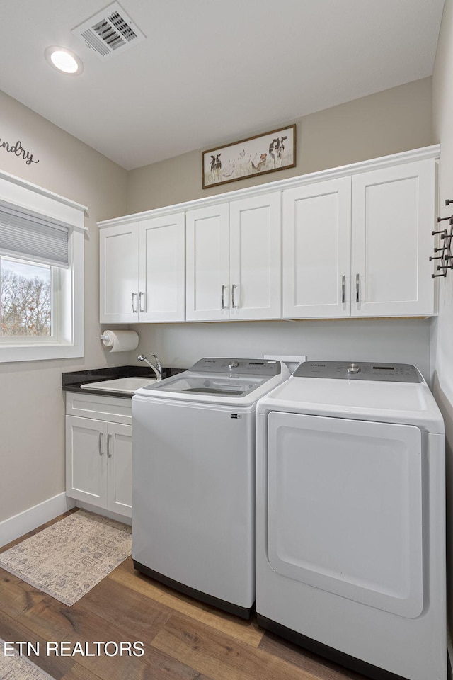 laundry area with cabinet space, visible vents, washer and clothes dryer, wood finished floors, and a sink