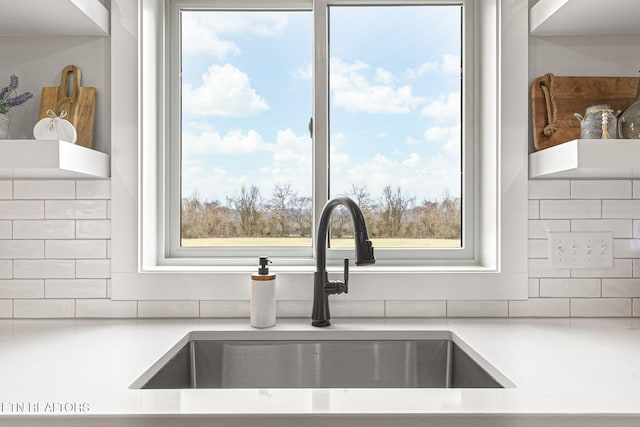 interior details featuring light countertops, tasteful backsplash, and a sink