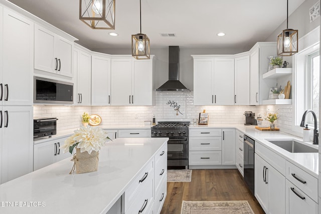 kitchen featuring a sink, light countertops, wall chimney range hood, black appliances, and pendant lighting