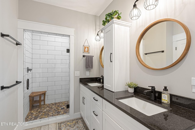 full bath with double vanity, a shower stall, and a sink