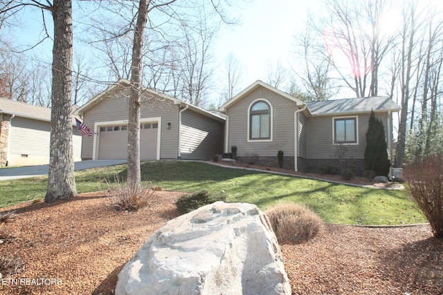 ranch-style home featuring an attached garage, driveway, and a front yard